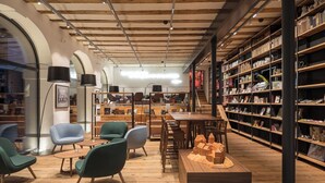 Een boekwinkel met houten vloeren, groene stoelen en boekenkasten.
