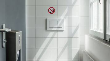 A modern bathroom with a toilet, a hand dryer, and a no-smoking sign.