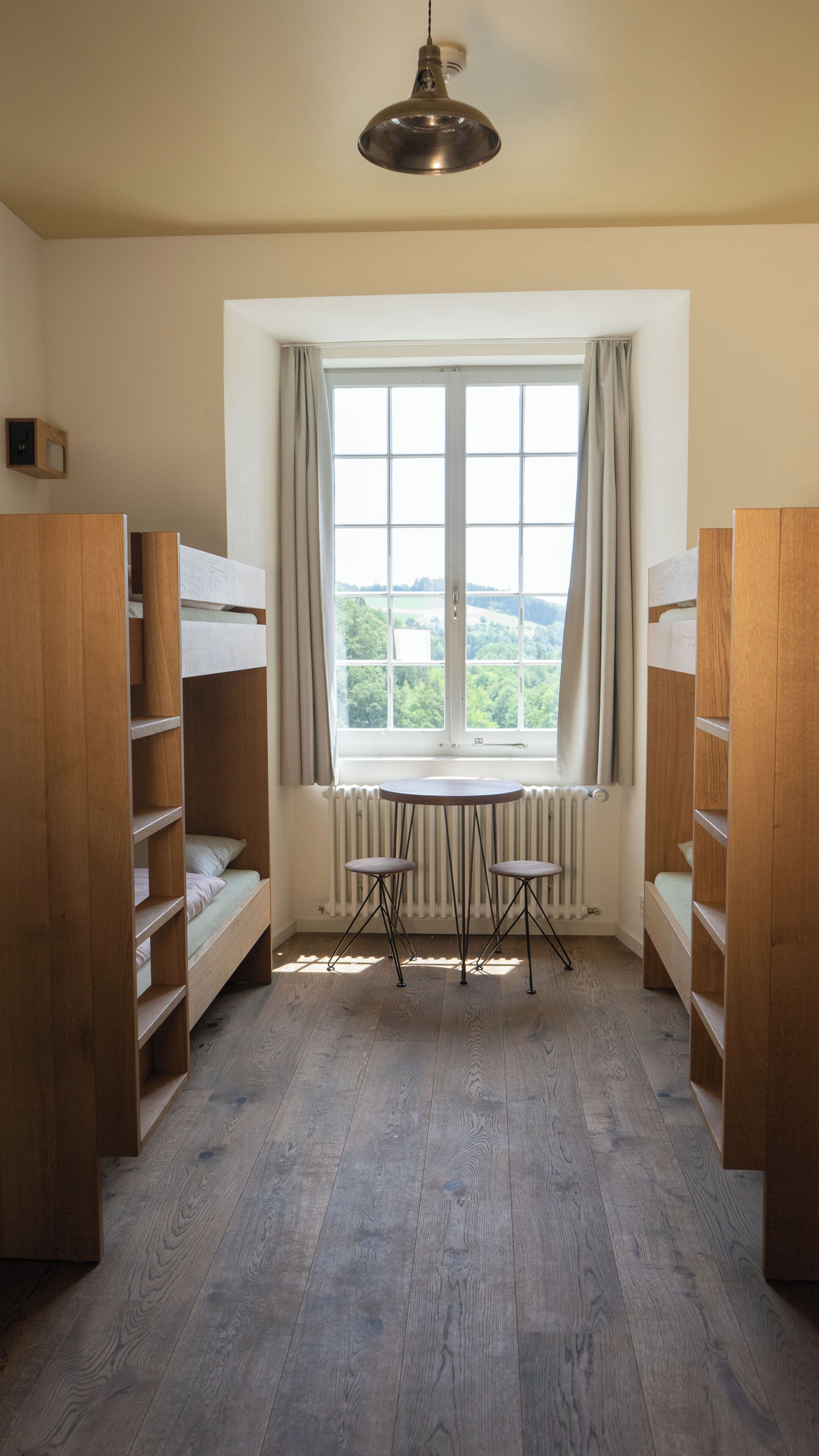 Ein Zimmer mit Etagenbetten, einem Tisch und einem Fenster mit Blick.