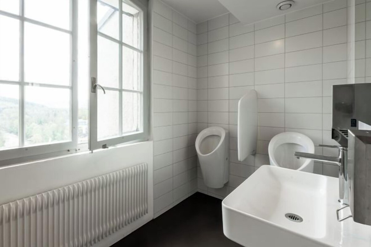 Een moderne badkamer met toilet, wastafel en raam.