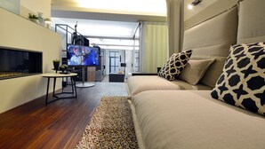A modern living room with a sofa, a TV, a small table, and a staircase leading to another level.