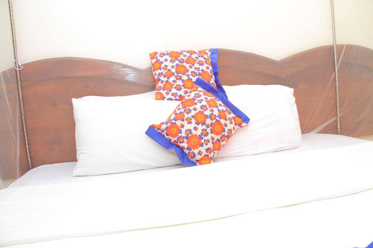 A bed with a wooden headboard, a white pillow, and a colorful floral blanket.