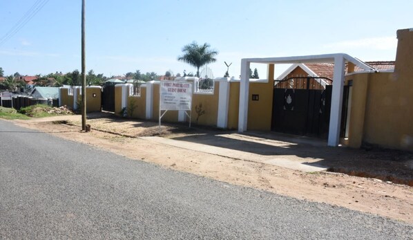 A gated property with a sign indicating it is a guest house. - Boulevard Excelsior Motel (Fort Portal)