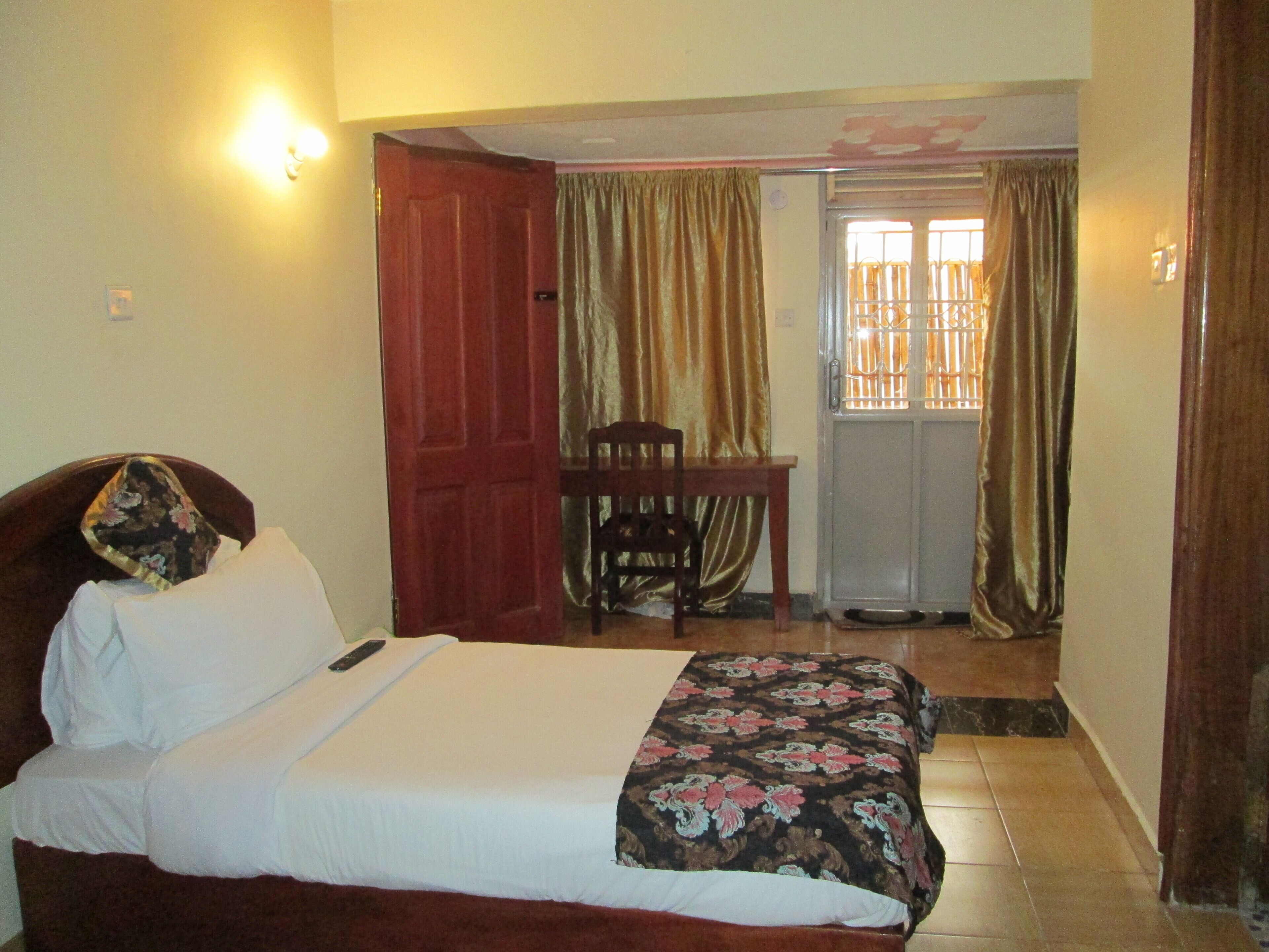 A bedroom with a bed, a chair, a desk, and a sliding door.