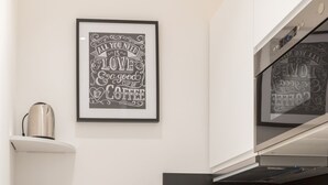 Eine moderne Küche mit weißen Schränken, einer schwarzen Arbeitsplatte, einem Edelstahltoaster und einem gerahmten Zitat an der Wand.