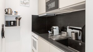 A modern kitchen with a black countertop, stainless steel appliances, and a hanging kitchen sign. - A3 Suite Studio 175Blo-Paris Convention (Paris-15E-Arrondissement)