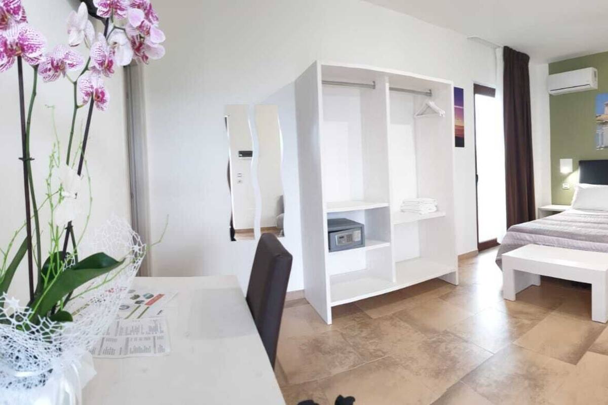A hotel room with a bed, a sofa, a desk, and a wardrobe.