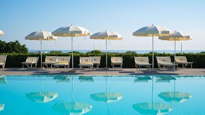A poolside area with lounge chairs and umbrellas, reflecting in the pool. - Torre Guaceto Greenblu Resort (Carovigno)