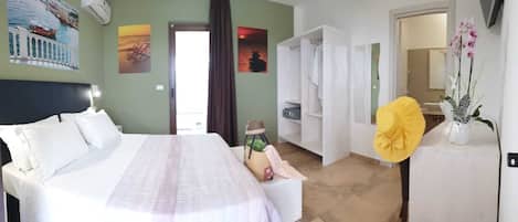 A hotel room with a bed, a wardrobe, a bathroom, and a view of the sea.