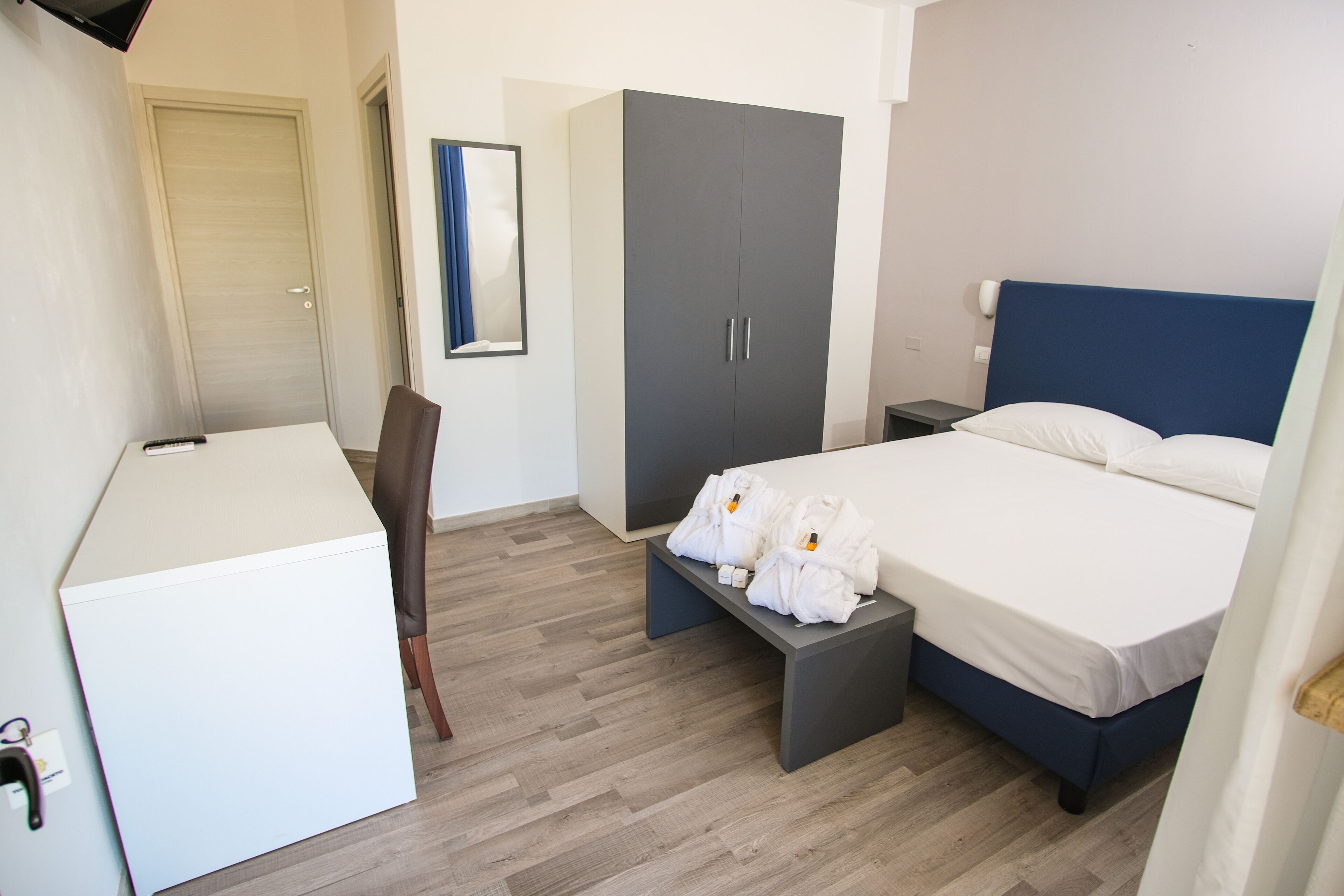 Ett hotellrum med en säng, sängbord, en garderob, ett skrivbord och en stol.