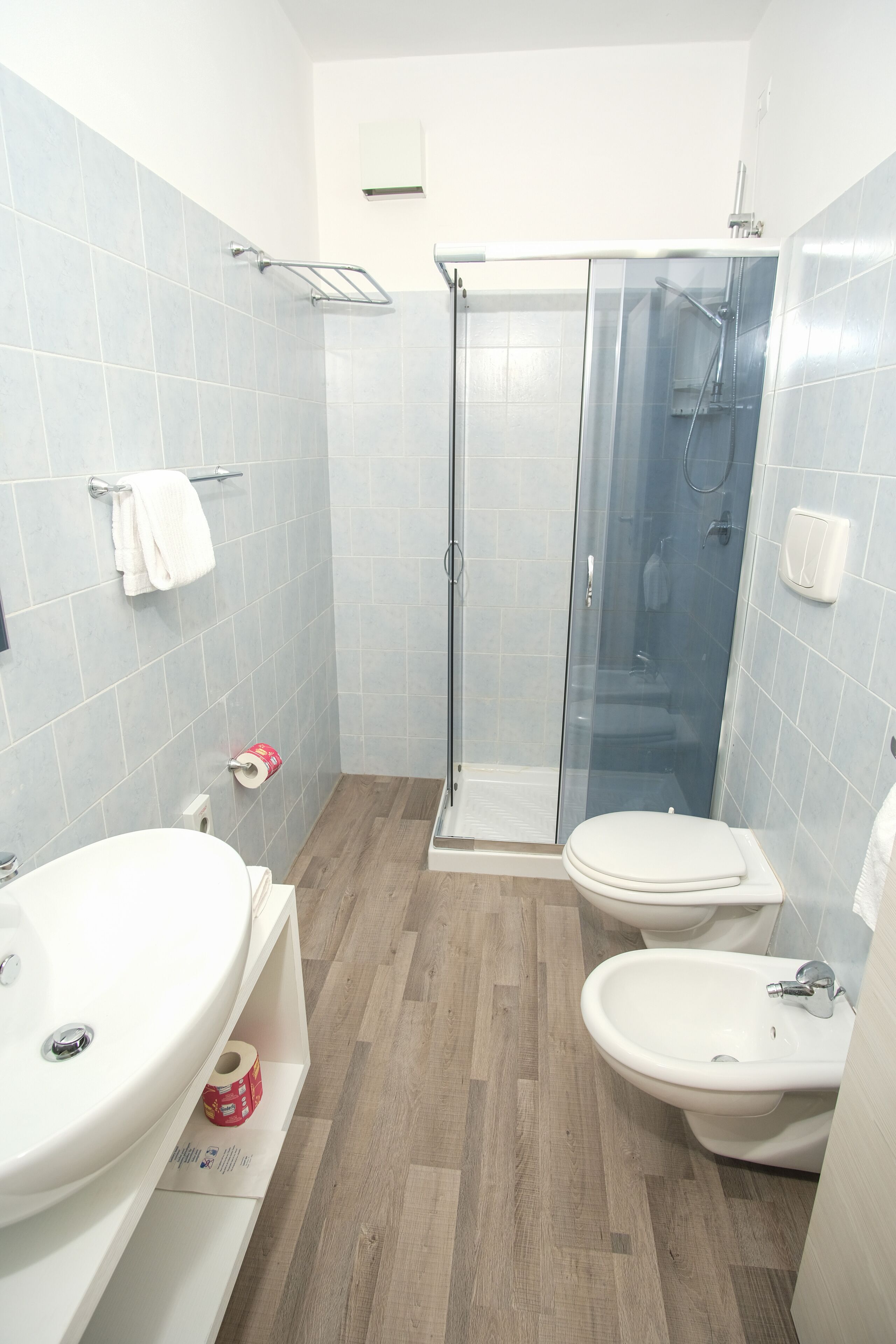 Une salle de bain moderne dotée d’une douche à parois de verre, de deux toilettes, d’un lavabo et d’un bidet.