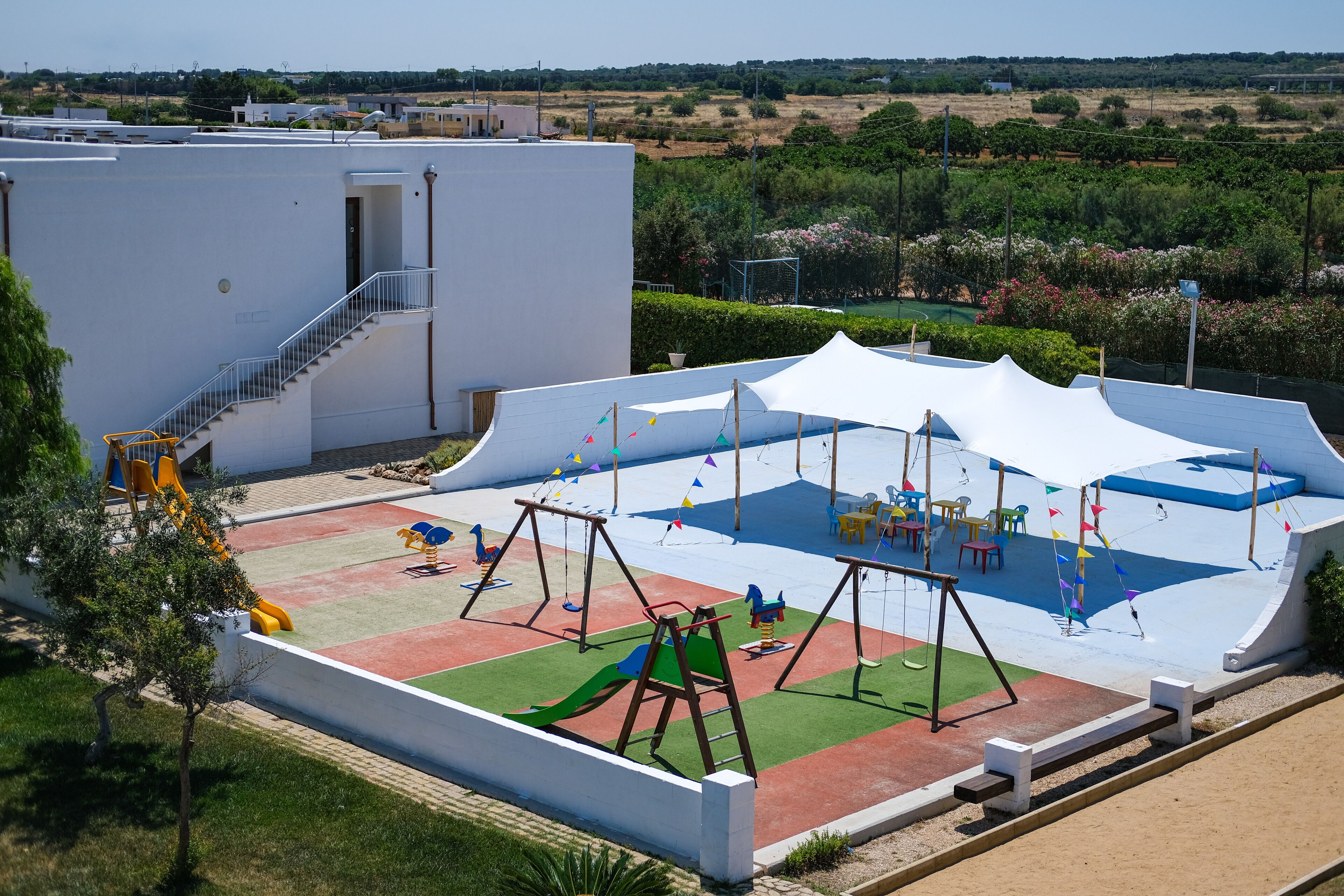 A playground with swings, slides, and a tent structure.