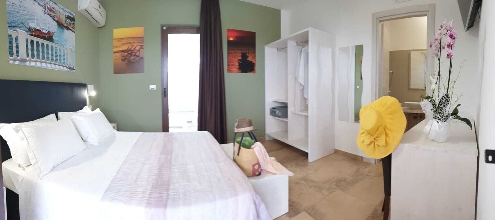 A hotel room with a bed, a wardrobe, a bathroom, and a view of the sea.