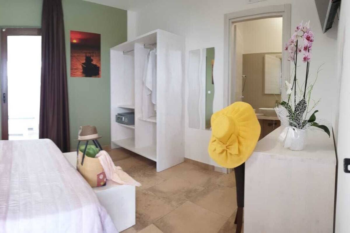 A hotel room with a bed, a wardrobe, a bathroom, and a view of the sea.