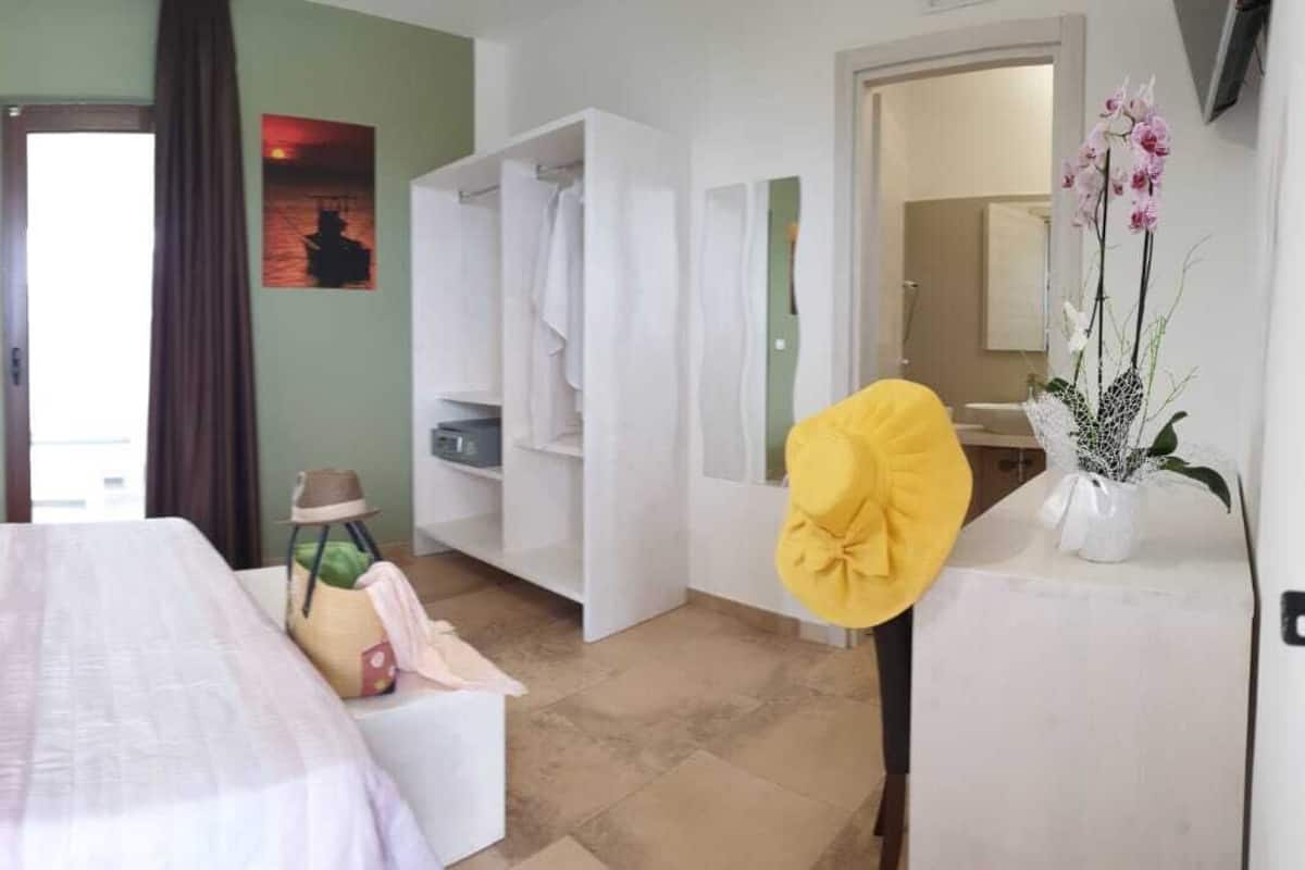 A hotel room with a bed, a wardrobe, a bathroom, and a view of the sea.