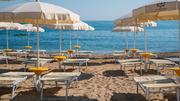 A beach with rows of white and yellow beach chairs and umbrellas, arranged neatly on the sand. - Torre Guaceto Greenblu Resort (Carovigno)