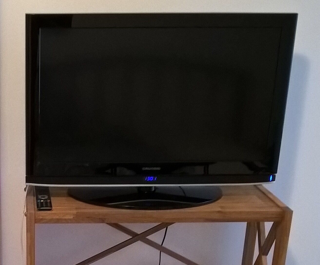 A flat-screen TV on a wooden stand with a remote control.