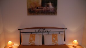 A neatly made bed with floral bedding, two bedside lamps, and a painting above the bed.