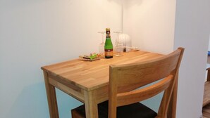 A wooden dining table with a chair, a bottle of champagne, and two wine glasses on the table.