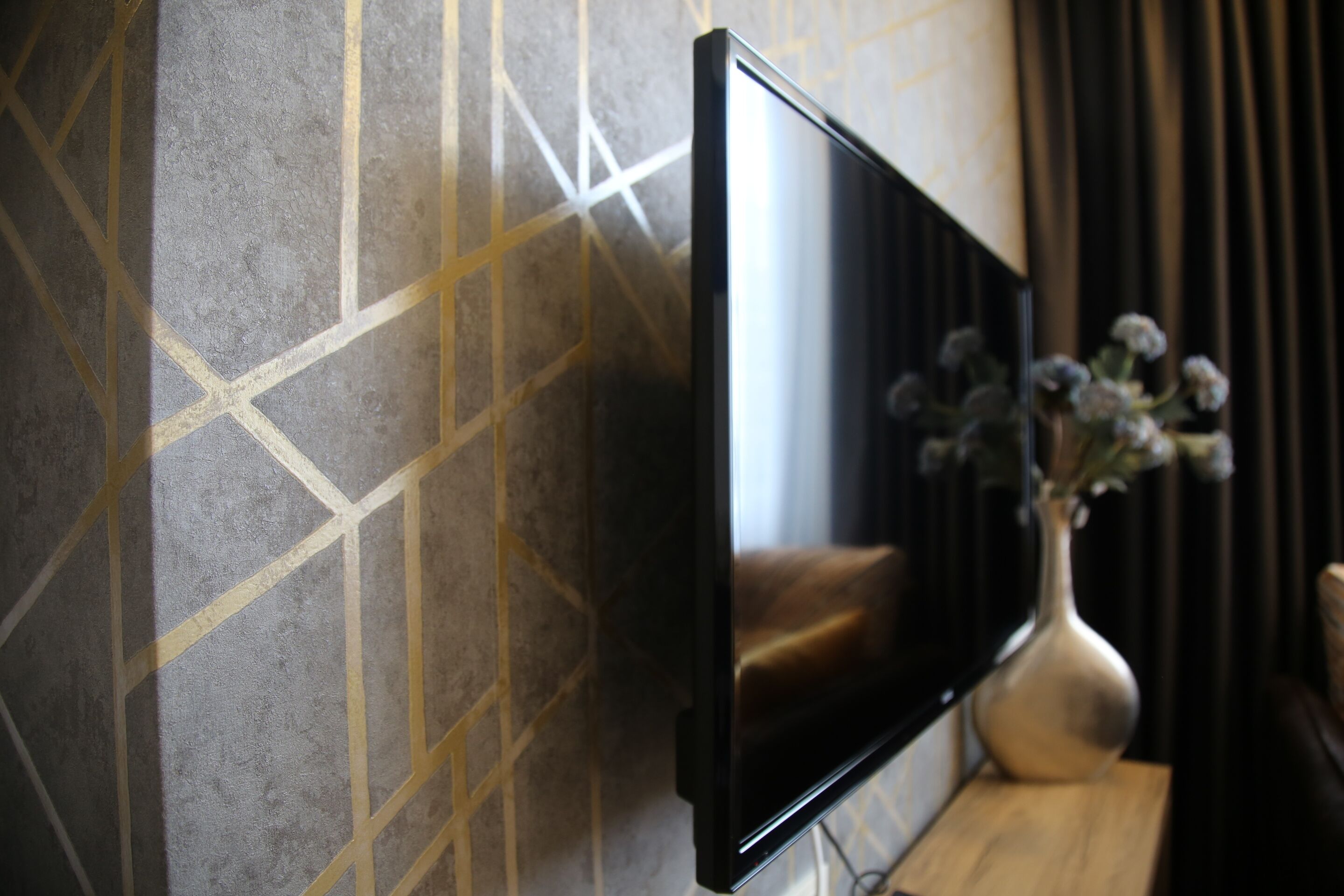 A flat-screen TV mounted on a wall with a geometric patterned design.