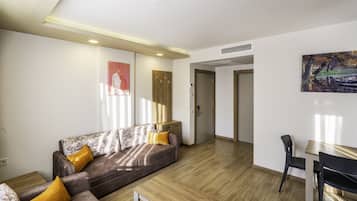 A modern living room with a sofa, coffee table, and a dining area with a chair and table.