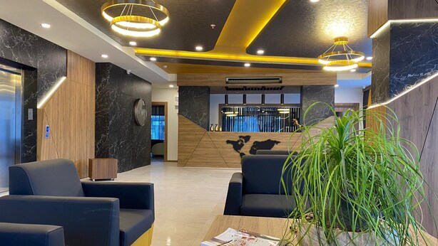 A modern reception area with a reception desk, seating, and a large plant. - Golden World Suite Hotel (Konyaalti)