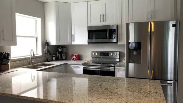 A modern kitchen with white cabinets, stainless steel appliances, and a granite countertop. - Hamlet by I-4 · New! 5 Bedroom Pool Villa. Sleep 15+ Orlando (Kissimmee)