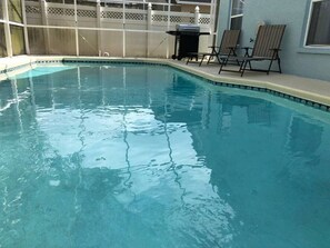 Une piscine aux eaux cristallines, bordée d’une terrasse blanche et dotée de chaises longues.