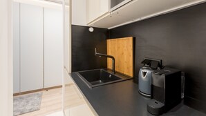Una cucina moderna con un piano di lavoro nero, un lavello in acciaio inossidabile, una macchina per il caffè e un armadietto in legno.