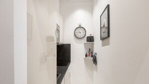 Un corridoio stretto con un bancone nero, pareti bianche e un orologio appeso al muro.