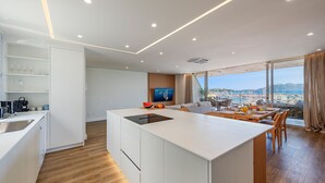 A modern kitchen with a central island, a dining area with a view, and a TV in the background. - Vistamar IV frontline sea Apt. in a prime location in Puerto Pollensa (Puerto Pollensa)