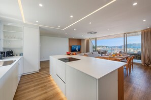 Una cocina moderna con una isla central, un área de comedor con vistas y un televisor al fondo.