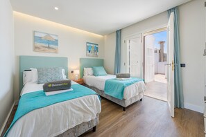 Habitación de hotel con dos camas, balcón y vista al mar.