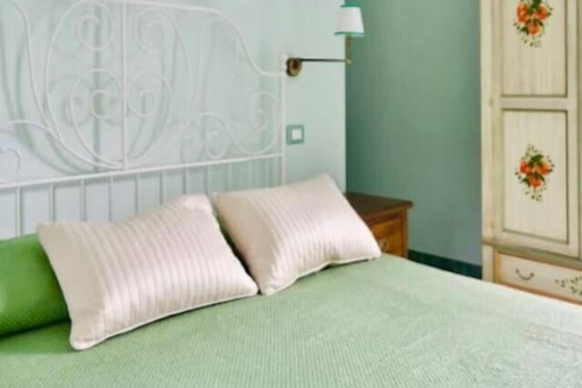 A bedroom with a bed, pillows, a wall-mounted lamp, and a wardrobe.