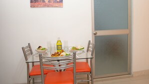 Uma mesa de jantar com cadeiras, uma garrafa de Inca Kola e pratos de comida.