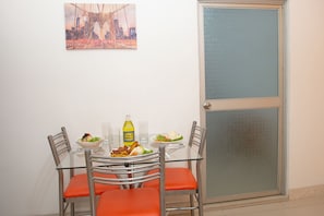 A dining table with chairs, a bottle of Inca Kola, and plates of food. - Atahualpa Suites Apartment Rentals (Iquitos)