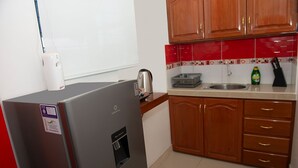 Uma cozinha compacta com geladeira, chaleira e armários de madeira.