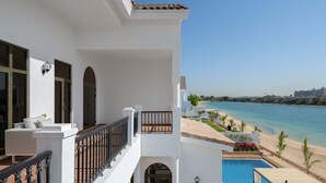 Uma varanda com vista para uma praia e uma piscina.