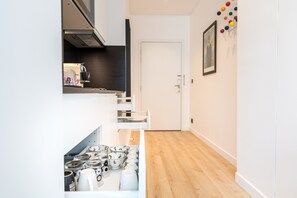 Una cocina estrecha con armarios blancos, una estufa y una encimera blanca.