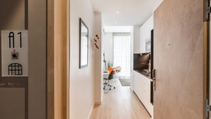 Une cuisine moderne dotée d’une grande cuisinière, un coin repas avec une table et des chaises, et un couloir avec une porte portant l’inscription « A1 ».