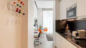 Une cuisine moderne équipée d’un four encastré, d’une machine à café et d’un four à micro-ondes. On y trouve un coin repas avec une table et des chaises, ainsi qu’un îlot de cuisine doté d’un évier.