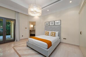 A modern bedroom with a large bed, a chandelier, and artwork on the wall.