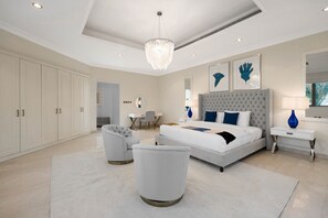 A modern bedroom with a large bed, a chandelier, a desk, and a chair.