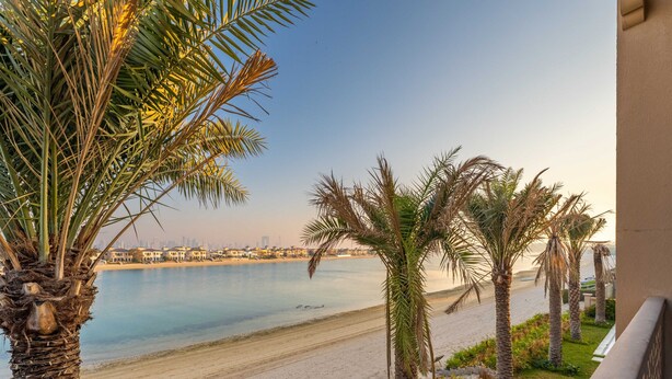 A beach view with palm trees and a cityscape in the background. - Exclusive Villa w/ Private Pool, Garden & Beach (Dubai)