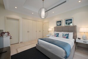 A modern bedroom with a large bed, bedside tables, a wardrobe, and a chandelier. - Exclusive Villa w/ Private Pool, Garden & Beach (Dubai)