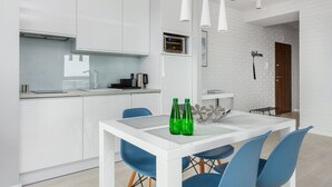 Eine moderne Küche mit weißen Schränken, einem Esstisch mit blauen Stühlen und einer Kaffeemaschine.