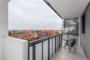 A balcony with a table and chairs, offering a view of buildings and a river.