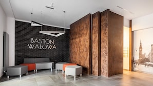 Eine moderne Lobby mit einer Wand aus schwarzen Ziegeln, einem grauen Sofa und orangenen Kissen.