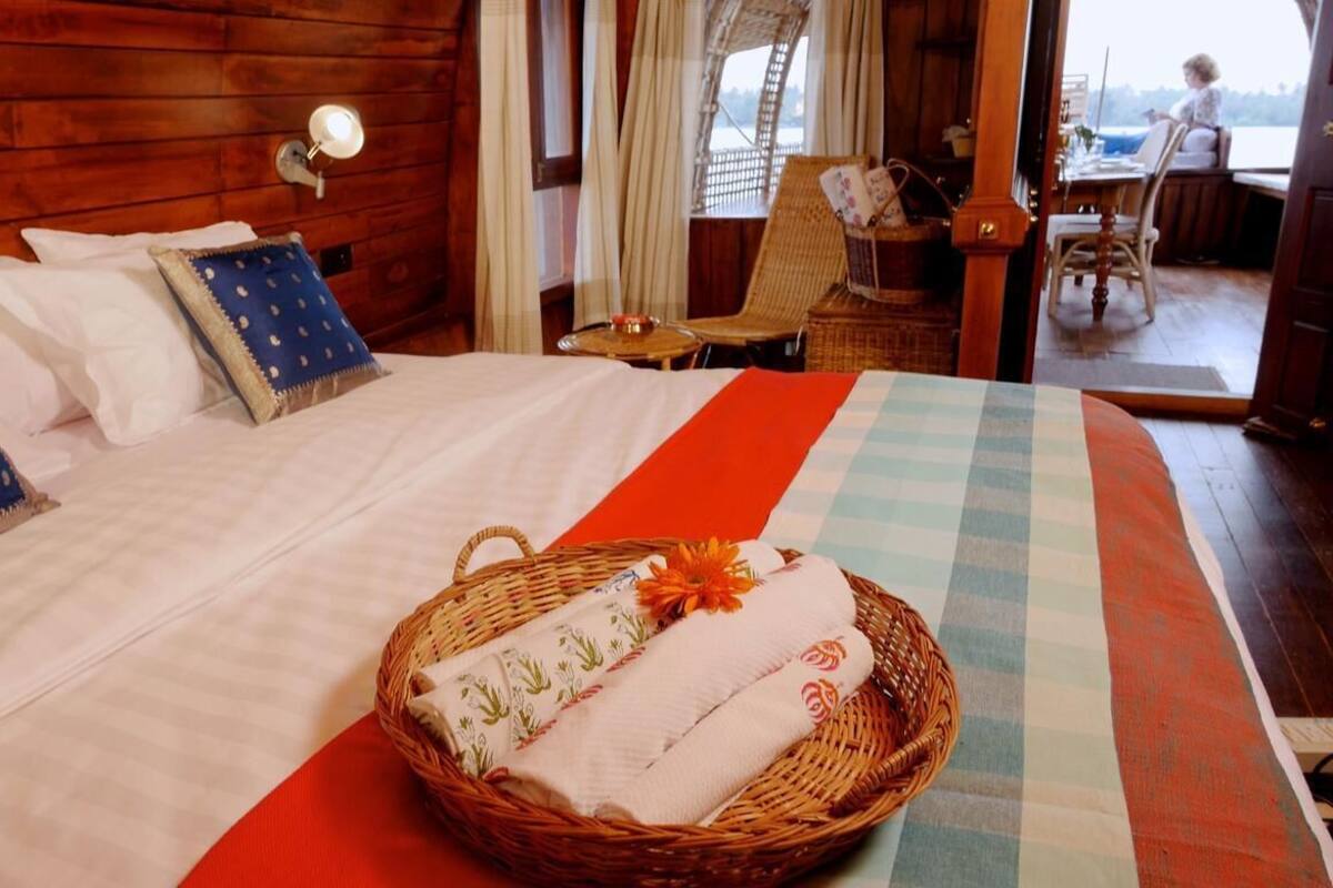 A wooden cabin bedroom with a bed, a wicker basket with towels, and a view of the outside.