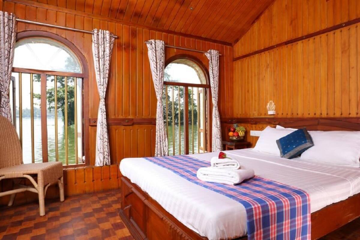 A wooden room with a bed, curtains, and a window.